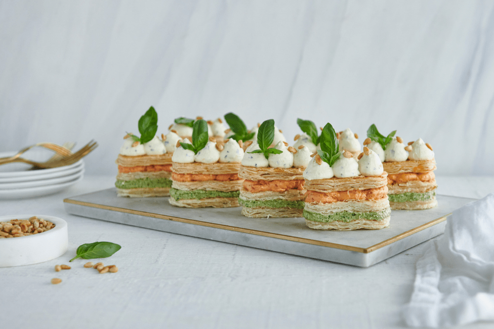 Absolutely stunning is the only way to describe these canapes. Pesto, tomato and capsicum, and zingy cream cheese and lemon layers are sandwiched between deliciously crisp butter puff pastry, then garnished with fresh basil and pine nuts to create a truly show-stopping dish that will make your guests gasp with delight!